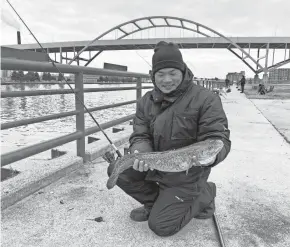  ?? PAUL A. SMITH ?? Andy Ko of Chicago holds a burbot he caught while fishing at the mouth of the Milwaukee River.