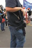  ??  ?? A Trump backer keeps a hand on his gun during the demonstrat­ion outside the office in Phoenix.