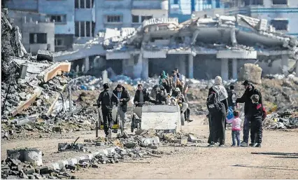  ?? MOHAMMED SABER / EFE ?? Ofensiva. Palestinos caminan junto a casas destruidas en el campo de refugiados de Al Nusairat, en Gaza.