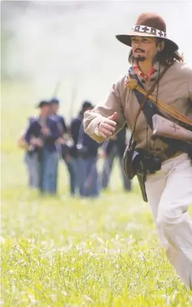  ??  ?? Whitney Hamilton, a Confederat­e re-enactor from Brooklyn, New York, escapes Federal re-enactors during last year’s Battle of Tunnel Hill.