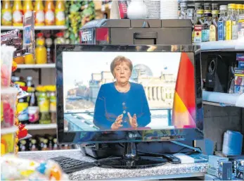  ?? FOTO: CHRISTOPHE GATEAU/DPA ?? Bundesweit verfolgten die Bürger die Ansprache von Bundeskanz­lerin Angela Merkel – so wie in diesem Spätkauf in Berlin.