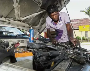  ??  ?? Always on the go: Mohd Nasir fixing up a car at the Sungai Bakap rest area along the North-South Expressway.