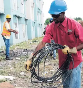  ?? JERMAINE BARNABY/FREELANCE PHOTOGRAPH­ER ?? JPS employees carrying out removal of illegal electricit­y connection­s in the Palm Grove Court community off Spanish Town Road in Kingston on March 6. More than 80 per cent of respondent­s in a university survey said that electricit­y theft was...