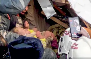  ?? AP ?? Emergency Situations employees save 11-month-old Ivan Fokin who had been trapped in a collapsed section of an apartment building in Magnitigor­sk.