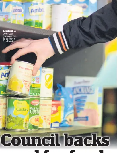  ??  ?? Essential A volunteer grabs an item to pack at a foodbank