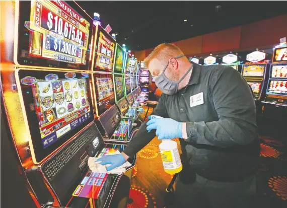  ?? JIM WELLS ?? Jeremy Rodominski, food and beverage manager at Century Casino in Balzac, north of Calgary, cleans touch points on slot machines on Tuesday. The casino, which will be allowed to reopen as of Friday in Stage 2 of Alberta’s plan, is preparing to open the doors when safely possible.