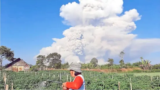  ?? BAHARI TARIGAN/AGENCE FRANCE-PRESSE ?? AS Mount Sinabung spews ash into the sky as seen from Karo, North Sumatra a farmer still finds time to tend to his farm.