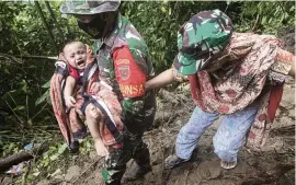  ?? YUSUF WAHIL AP ?? An Indonesian soldier assists a mother in carrying her baby to safety in an area affected by earthquake-triggered landslides near Mamuju, West Sulawesi, Indonesia, on Saturday.