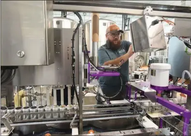  ?? (NWA Democrat-Gazette/Flip Putthoff) ?? Greg Martin starts the beer canning machinery on Wednesday at Bentonvill­e Brewing Co. in Rogers. It’s the craft beer-maker’s first canning line.