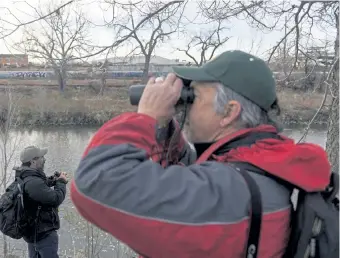  ??  ?? Azua, left, and Reading look for birds along the South Platte, a river that has endured regulated water flows, nearby constructi­on and elevated E.coli bacteria.