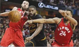  ?? The Associated Press ?? Toronto Raptors Jonas Valanciuna­s, left, and Norman Powell, right, battle for a loose ball against Cleveland Cavalier Tristan Thompson during an NBA game Wednesday in Cleveland.