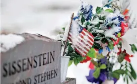  ?? [PHOTO BY JIM BECKEL, THE OKLAHOMAN] ?? American flags, some partially obscured by snow, decorate a grave Monday in observance of Veterans Day at Kolb Cemetery in Spencer.