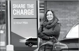  ?? ASSOCIATED PRESS ?? NEDA DEYLAMI poses for a portrait while charging her electric vehicle at a Chicago area grocery store. Owners of electric vehicles in a number of states will start seeing fees to pay for road repairs in the new year.