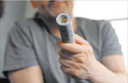  ?? Shafkat Anowar The Associated Press ?? Troy Hernandez, an environmen­tal justice activist with Pilsen Environmen­tal Rights and Reform Organizati­on, shows a piece of lead pipe obtained from his residence during his home renovation on April 9 in Chicago’s Pilsen neighborho­od.