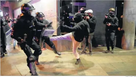  ?? TONI ALBIR / EFE ?? Un manifestan­te por la encarcelac­ión de Pablo Hasel se enfrenta anoche a dos agentes de los Mossos en Barcelona.