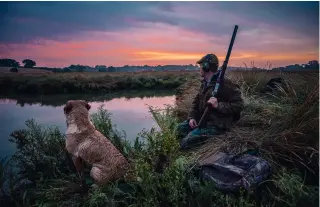  ?? ?? Simon Garnham and his faithful lab enjoy the sunrise as they wait for birds in Brightling­sea, Essex