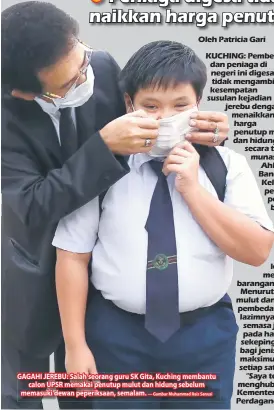  ?? — Gambar Muhammad Rais Sanusi ?? GAGAHI JEREBU: Salah seorang guru SK Gita, Kuching membantu
calon UPSR memakai penutup mulut dan hidung sebelum memasuki dewan peperiksaa­n, semalam.