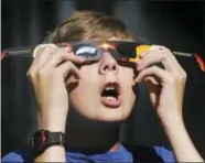  ?? SCOTT G WINTERTON — THE DESERET NEWS VIA AP ?? In this Wednesday photo, Colton Hammer tries out his eclipse glasses he bought from the Clark Planetariu­m in Salt Lake City in preparatio­n for the eclipse.