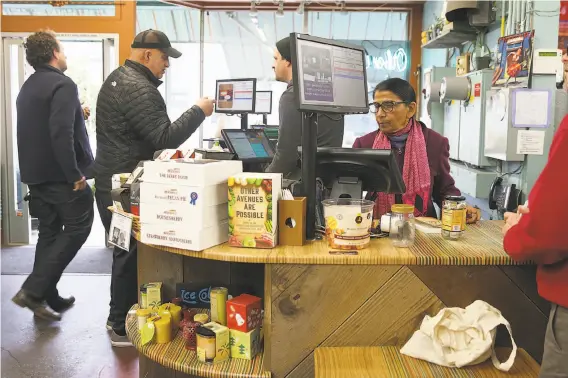  ?? Liz Hafalia / The Chronicle ?? Shanta Nimbark Sacharoff (in pink scarf) works behind the counter at Other Avenues co-op in the Sunset District of S.F.
