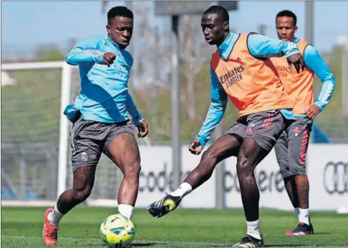  ??  ?? Mendy golpea la pelota ante Vinicius en una acción del entrenamie­nto de ayer en Valdebebas.