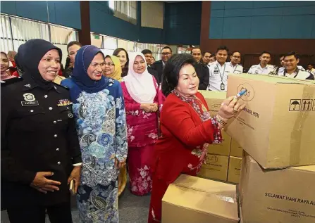  ??  ?? Lending a hand: Rosmah labelling one of the care packages at the Bakti Building in Kuala Lumpur. Looking on are Bakti honorary secretary Datin Seri Khamarzan Ahmed Meah (in blue) and Deputy Supt Fatimah Ahmad of Bukit Aman (left), as well as...