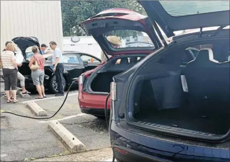  ?? MONICA SAGER — DIGITAL FIRST MEDIA ?? In this photo, electric cars are being charged, while people look at electric vehicles on display at the Boyertown Museum of Historic Vehicles. There are now four Tesla and two universal connectors to charge electric vehicles at the museum .