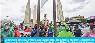  ?? — AFP ?? BANGKOK: Pro-democracy protesters push a fake guillotine past Democracy Monument as they march to Government House to call for the resignatio­n of Thailand’s Prime Minister Prayut Chan-O-Cha in Bangkok yesterday.