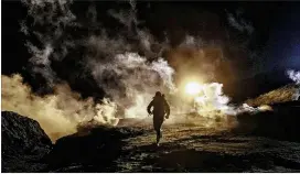  ?? ASSOCIATED PRESS ?? Migrants try to outrun tear gas being fired by U.S. Border Protection officers to the Mexican side of the border fence on Tuesday. Some migrants had climbed the fence to get to San Diego from Tijuana.