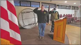  ??  ?? With tables and chairs stacked against the wall of their rental hall space, DeOld (left) and Veterans of Foreign War Post 1018 Board of Directors member Grady Durden salute the flag at the start of an online post meeting in Boston.