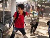  ??  ?? TWO LITTLE BOYS: Two young children hold hands as they run away from clashes with Mexican National Guards after their migrant caravan crossed on foot from Guatemala to Mexico last week
