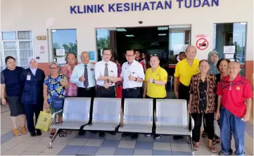  ??  ?? Lee hands over the four-seater chairs to Tudan polyclinic officer-in-charge Dr Maurice Steve Utap (sixth left), witnessed by staff, patients and members of the public.