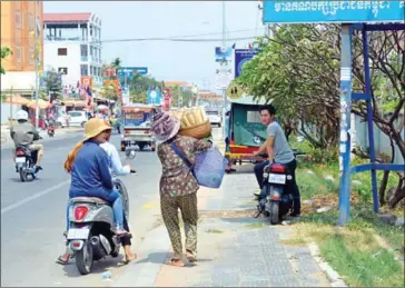  ?? ERIN HANDLEY ?? Huoch Yav, 60, walks on the streets of Takhmao this week, sells bamboo cylinders packed with rice for 2,000 riel apiece. After her husband died, she needed a way to provide for herself and her family.