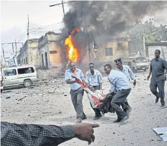  ??  ?? DOWN IN FLAMES: A wounded civilian is carried away from a bomb blast site in Mogadishu in 2013.