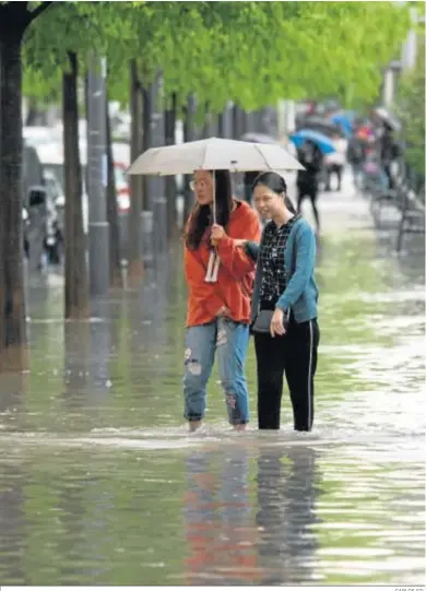  ?? CARLOS GIL ?? Dos transeúnte­s intentan avanzar por una inundada calle Gonzalo Gallas.