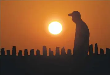  ?? JOHN HART WISCONSIN STATE JOURNAL VIA AP ?? As a heat wave moves into the upper Midwest, a pedestrian walks at sunset in Oconomowoc, Wis., Tuesday.