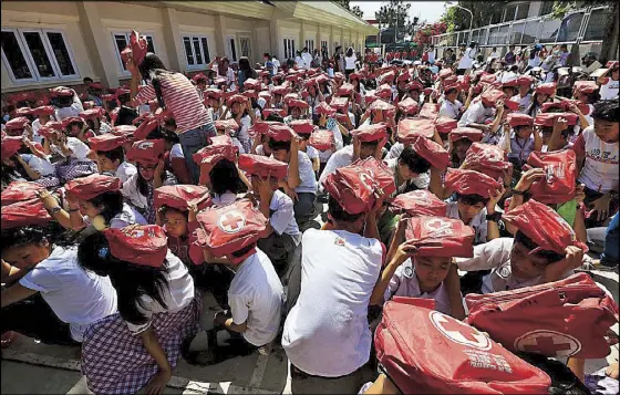  ?? EDD GUMBAN ?? Students cover their heads with first aid kits during an earthquake drill at the Taguig Science High School in Barangay San Miguel, Taguig yesterday. Government disaster management offices held a nationwide earthquake and fire drill aimed at...