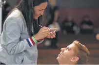  ??  ?? Oriana Encarnacio­n helps dancer Javier Gil, from Houston, finish his makeup before his audition on Friday.