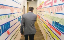  ??  ?? Warriors President Rick Welts walks by a pasteup progress board in Chase Center constructi­on offices.