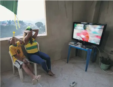  ?? JOE RAEDLE/Getty Images ?? Veronica Silva and her son, Gustavo, in the favela known as Falete in Rio de Janeiro, watch Brazil play against Mexico.