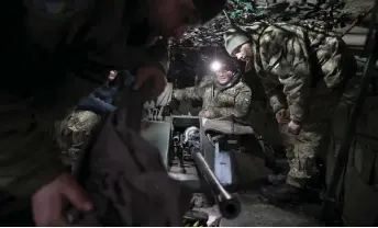  ?? — AFP photo ?? Ukrainian servicemen install an automatic cannon after preventive maintenanc­e on an armoured military vehicle at a workshop in the Donetsk region.