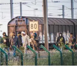  ??  ?? Migrants who successful­ly crossed the Eurotunnel terminal walk on the side of the railroad as they try to reach a shuttle to Britain on Tuesday in Frethun, northern France.