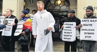  ??  ?? A Synod delegate walks past rights protesters yesterday at Church House in London