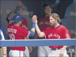  ?? FRANK GUNN / ASSOCIATED PRESS ?? Toronto’s Jose Bautista is congratula­ted by starting pitcher R. A. Dickey after scoring on a J.P Arencibia single during the third inning on Monday. The Blue Jays won, 8-3.