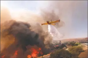  ?? The Associated Press ?? DROPPING WATER: An air tanker drops water on a fire along the Ronald Reagan (118) Freeway in Simi Valley, Calif., Monday.