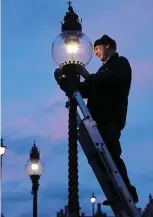  ?? ?? Soft glow: A British Gas engineer cleans a lamp in Westminste­r