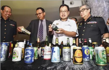  ??  ?? Chong (second right) takes a closer look at one of the beer brands. Seen at left is Rosli.