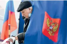  ?? OLGA MALTSEVA/GETTY-AFP ?? A voter examines the ballot Sunday during the last day of the three-day parliament­ary and local elections in Saint Petersburg, Russia.