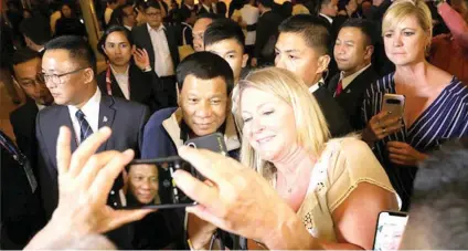  ?? PRESIDENTI­AL FOTO ?? SELFIE. President Rodrigo Duterte poses for a selfie with a foreigner as he gets a warm welcome upon his arrival at the Ritz Hotel in Singapore. /