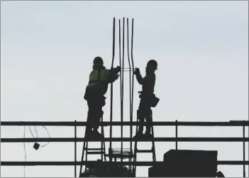  ?? AP PHOTO/MATT ROURKE ?? Constructi­on workers work on a building in Philadelph­ia, on Dec. 21.