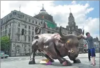  ?? YAN DAMING / FOR CHINA DAILY ?? A tourist poses in front of the bull statue at the Bund in Shanghai. The city has progressed in rankings of global financial centers.